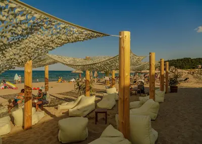 a beach with white chairs and umbrellas on the beach at Green Line Villa Sozopol in Sozopol