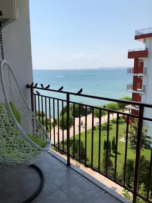 a balcony with a chair and a view of the beach at Fort Noks - Marina View in Sveti Vlas