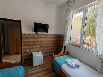 a room with two beds and a tv on the wall at Къща за гости Пиргос in Burgas City