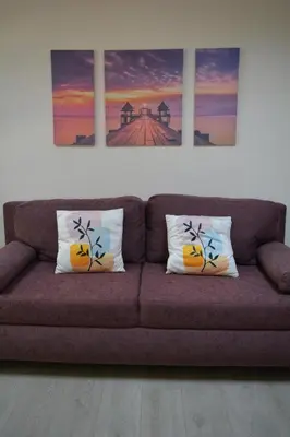 a couch in a living room with two paintings on the wall at City Center Apartment with a Backyard in Burgas City