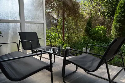 three chairs and a glass table on a porch at City Center Apartment with a Backyard in Burgas City