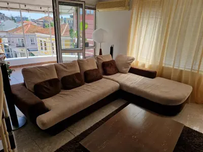a brown couch in a living room with a window at Comfort Flat in Burgas City