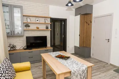 a living room with a table and a tv at Alagen Apartments Burgas in Burgas City