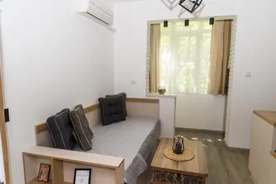 a small bedroom with a bed and a table at Alagen Apartments Burgas in Burgas City