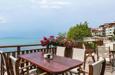 a wooden table and chairs on a balcony overlooking the ocean at Garden of Eden - Apartament Niya in Sveti Vlas