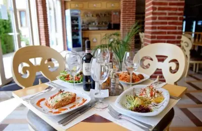 a table with plates of food and wine glasses at Garden of Eden - Apartament Niya in Sveti Vlas