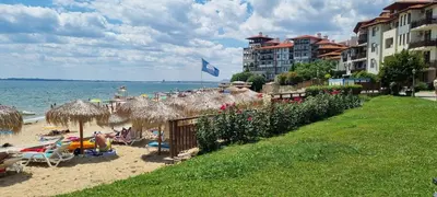 a beach with umbrellas and people sitting on the sand at Garden of Eden - Apartament Niya in Sveti Vlas