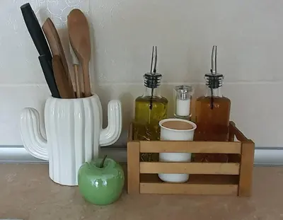 a vase with wooden utensils and a green apple at Ika apartment in Burgas City