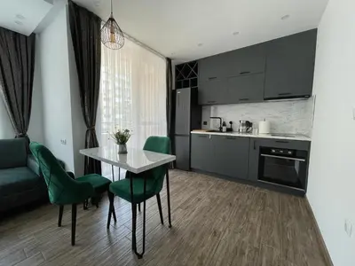 a kitchen and living room with a table and green chairs at Studio Green Зелено Студио in Burgas City