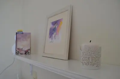 a white mantle with a picture and a candle on it at Апартамент в Oasis beach Kamchia - Стъпки в пясъка in Kamchia