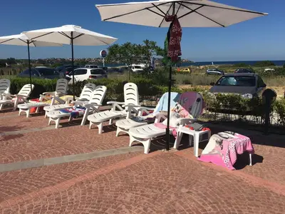 a row of chairs and umbrellas on a sidewalk at Bułgaria na lato apartament z widokiem na morze Sozopol in Sozopol