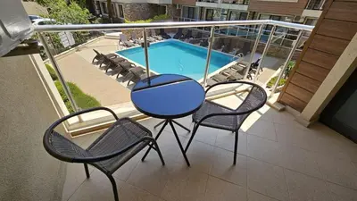 a balcony with a table and chairs and a swimming pool at Horizont Apartment Sozopol in Sozopol