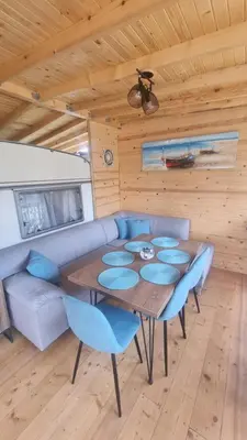a dining room with a table and blue chairs at Каравана Тиана in Sozopol
