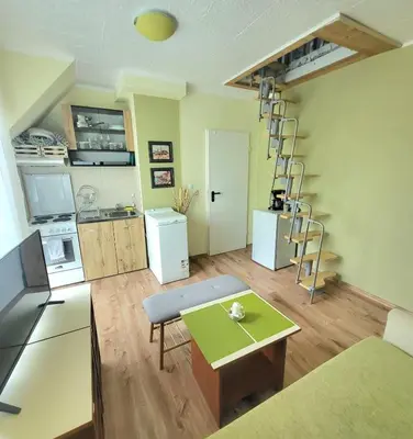 a room with a kitchen with a table and a ladder at Penthouse Apartments PERLA, Vasiliko in Tsarevo