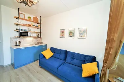 a living room with a blue couch and a kitchen at Design Studio in Atlantis Resort&SPA, Burgas Airport in Burgas City