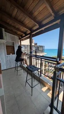a person sitting on a balcony looking out at the ocean at Apartament Piero in Pomorie
