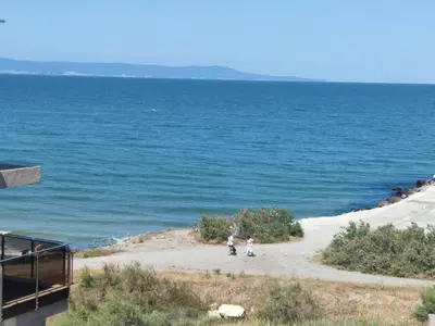 two people walking on a beach near the water at Apartament Piero in Pomorie