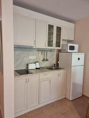 a kitchen with white cabinets and a sink and a refrigerator at Prestige Fort Beach apartment, Studio in Sveti Vlas