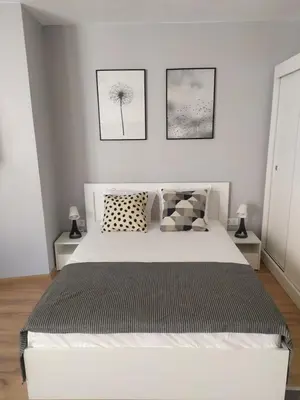 a bedroom with a white bed and two pictures on the wall at Студио Ирма in Burgas City