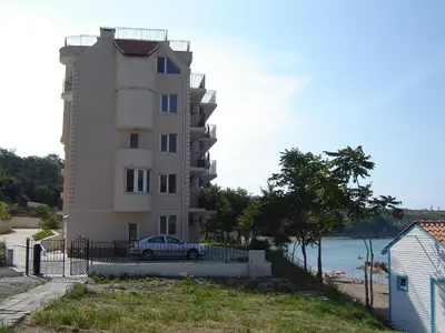 a building with a car parked next to the ocean at Villa Lazuren Bryag 2 in Chernomorets