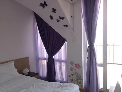 a bedroom with purple curtains and a bed and a window at Villa Lazuren Bryag 2 in Chernomorets