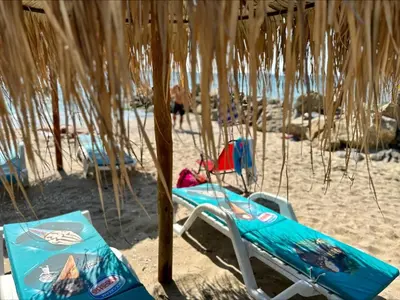 a pair of beach chairs sitting under a umbrella on the beach at Ipanema Beach - Menada Apartments in Sveti Vlas