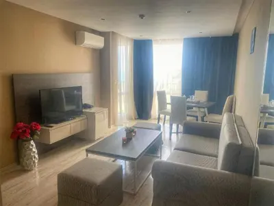 a living room with a couch and a tv and a table at Sea View Apartment In PARADISO in Nesebar