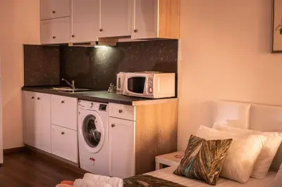 a kitchen with a washing machine and a microwave at bellissimo студио близо до плажа in Ravda
