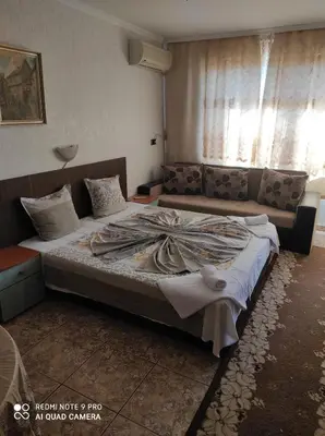 a bedroom with a large bed with a couch at Violeta 7 Guest House in Nesebar