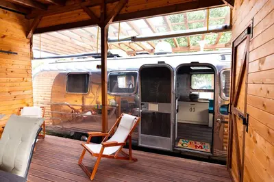 a porch with a chair and a van in a cabin at Luxury Vintage Airstream RV/Caravan Retro Charm Meets Comfort in Kiten