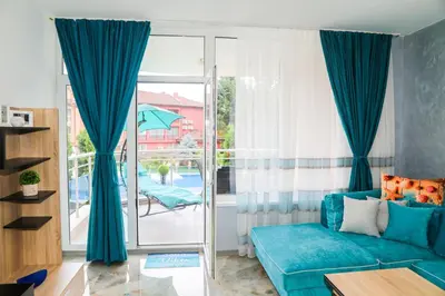 a living room with a blue couch and a balcony at Luxury First Line apartment with pool and sea view in complex Oazis in Ravda