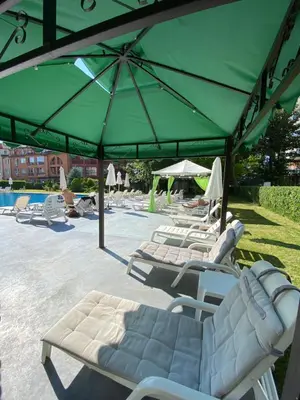 a group of lawn chairs and umbrellas next to a pool at Luxury First Line apartment with pool and sea view in complex Oazis in Ravda
