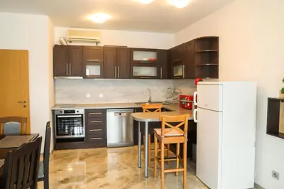 a kitchen with a table and a white refrigerator at Luxury First Line apartment with pool and sea view in complex Oazis in Ravda