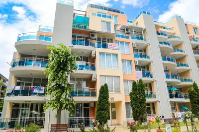 an apartment building with balconies and trees at Luxury First Line apartment with pool and sea view in complex Oazis in Ravda
