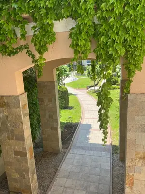 a walkway under a building with green trees at Green Life Private SP apartments -Sozopol in Sozopol