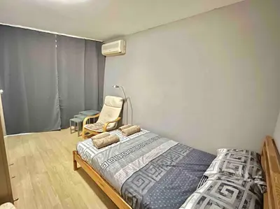 a bedroom with a bed and a chair at By The Sea Apartment in Varna City