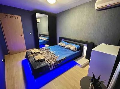 a bedroom with a bed with a blue light on it at By The Sea Apartment in Varna City