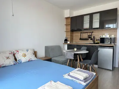 a bedroom with a blue bed and a kitchen at Ив-Бо in Ravda