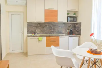 a kitchen with white cabinets and a table and chairs at Central location and FREE parking in Varna City