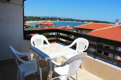a table and chairs on a balcony with a view of the water at Kapriz Apartment in Kiten