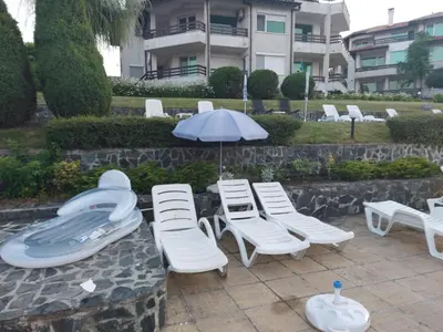 a group of lounge chairs and an umbrella and an inflatable at Kapriz Apartment in Kiten