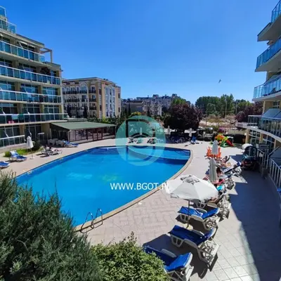 a swimming pool in a resort with chairs and umbrellas at Sunny Holiday - Cacao Beach Apartments in Sunny Beach