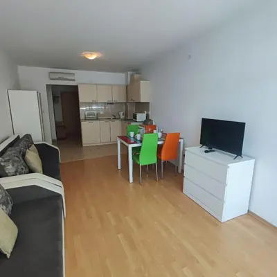 a living room with a couch and a table with a television at Sunny Holiday - Cacao Beach Apartments in Sunny Beach