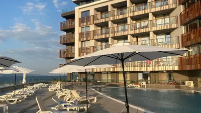 a pool with chairs and umbrellas in front of a building at PARADISO 'В' 201 One Bedroom Apartment in Nesebar