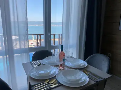 a table with plates and utensils and a view of the ocean at PARADISO 'В' 201 One Bedroom Apartment in Nesebar