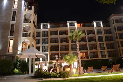a hotel at night with an umbrella and palm trees at Harmony Suites Jungle - Family Friendly Complex in Sunny Beach