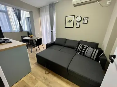 a living room with a black couch and a table at Sea Garden Apartment in Burgas City