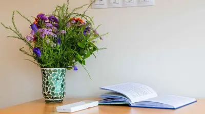 a vase of flowers and a book on a table at Central DELUXE Apartment in Burgas City