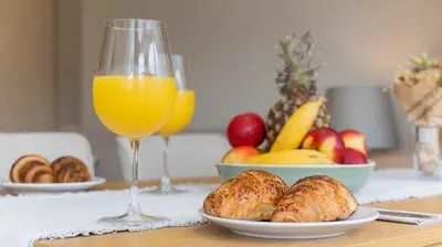 a table with a plate of bread and a glass of orange juice at Central DELUXE Apartment in Burgas City
