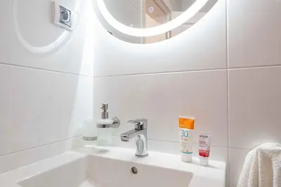 a white bathroom with a sink and a mirror at Central DELUXE Apartment in Burgas City